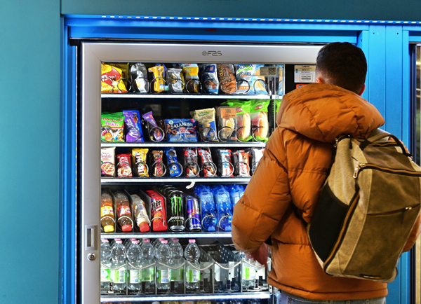 estudiante comprando un alimento de una máquina expendedora
